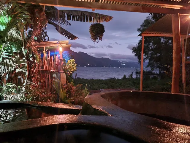 Nighttime view of Los Termales hot spring pools lit with colorful lights, overlooking Lake Atitlan and mountains in Guatemala.