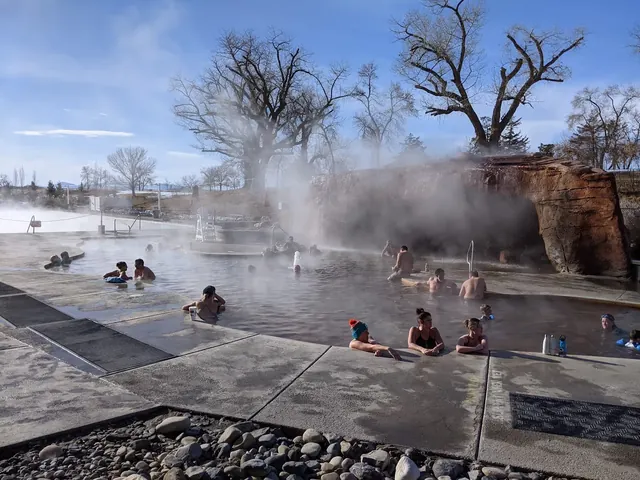 Daytime soaking pool at Crystal Hot Springs surrounded by bare trees, concrete deck, steam, and people enjoying the warm mineral water.