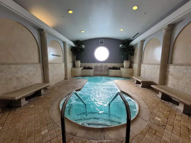 Indoor spa pool with bubbling water at Glen Ivy Hot Springs featuring tiled walls, benches, decorative plants, and a round window.