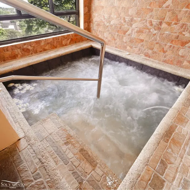Indoor bubbling hot spring soaking pool with stone tile walls and metal handrails at Sol Y Viento Hotels and Resorts near Calamba City Phil.