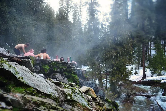Group of people relaxing in a steaming stone hot spring pool at Weir Creek Hot Springs near Kooskia, Idaho, United States.