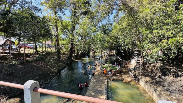 Outdoor hot spring soaking pools at Hin Dad Hot Spring in Thong Pha Phum, Thailand surrounded by trees on a sunny day.