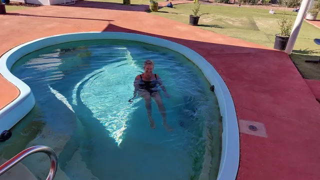 A woman sitting relaxed in a round blue hot spring pool at Yowah Artesian Pools in Yowah Queensland Australia.