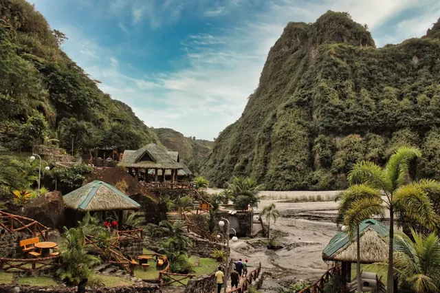 Rocky terrain near lush green hills with scattered palm trees forms the outdoor area of Puning Hot Springclose to Angeles City Philippines.