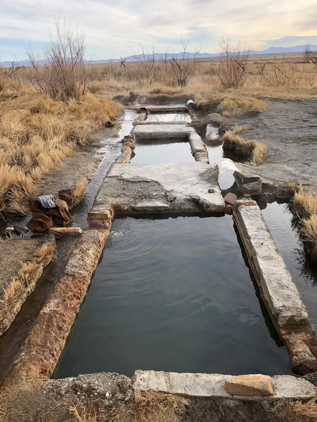 Rectangular manmade pools at Baker Hot Springs with visible steam and dry grasslands near Delta, Utah in the background.