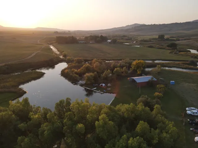 Aerial view of Gigantic Warm Spring shows a large water pool bordered by green fields and trees near Lewistown Montana.